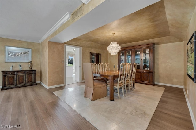 dining space featuring light hardwood / wood-style floors, ornamental molding, and a notable chandelier