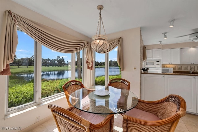 tiled dining space featuring a water view and ceiling fan