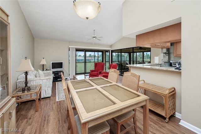 dining room with ceiling fan, vaulted ceiling, and hardwood / wood-style flooring