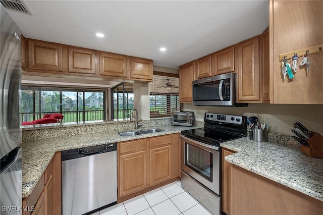 kitchen featuring light tile patterned flooring, sink, light stone countertops, and stainless steel appliances