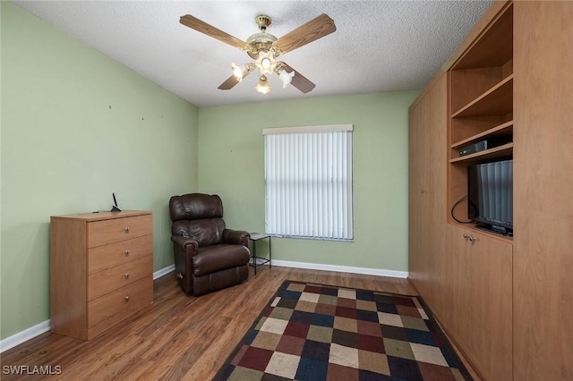 living area with a textured ceiling, ceiling fan, and dark wood-type flooring