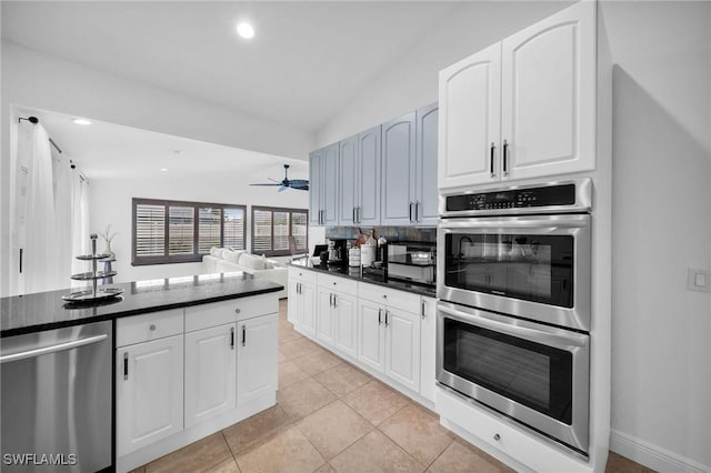 kitchen featuring stainless steel appliances, dark countertops, white cabinets, and lofted ceiling