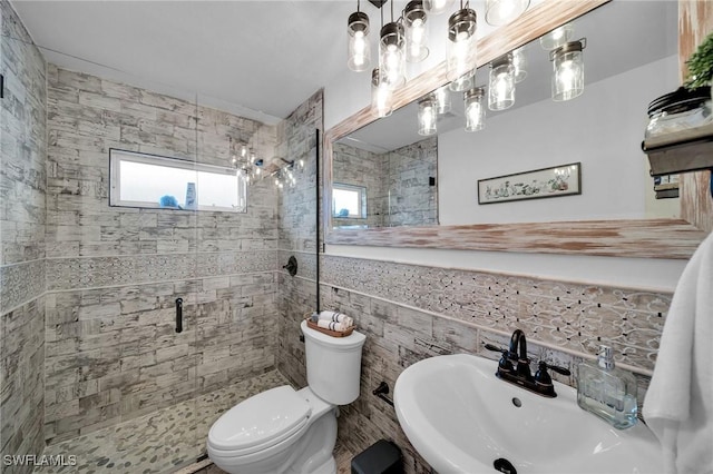 full bath with tile walls, toilet, wainscoting, a sink, and a shower stall