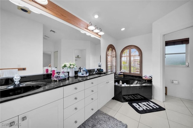 bathroom with a bath, tile patterned flooring, double vanity, and a sink