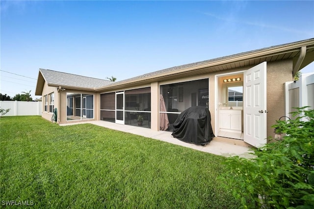 rear view of property with a yard, fence, a sunroom, and stucco siding