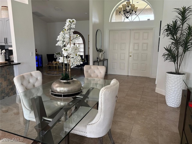 tiled dining room with baseboards and a chandelier