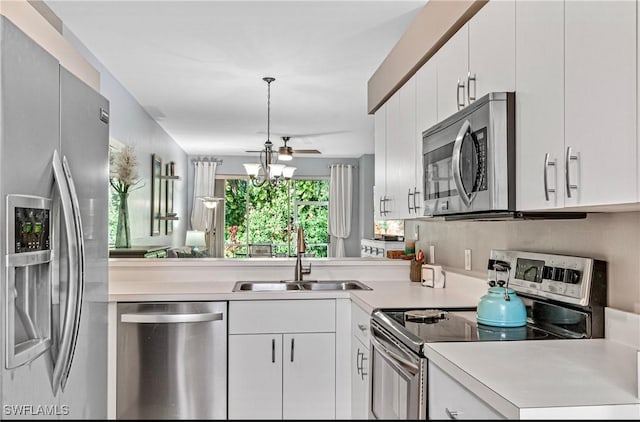 kitchen featuring sink, white cabinets, stainless steel appliances, and decorative light fixtures