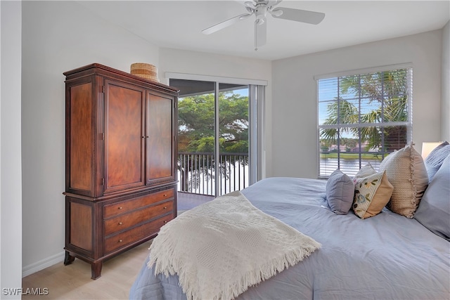 bedroom featuring ceiling fan, light hardwood / wood-style flooring, access to exterior, and a water view