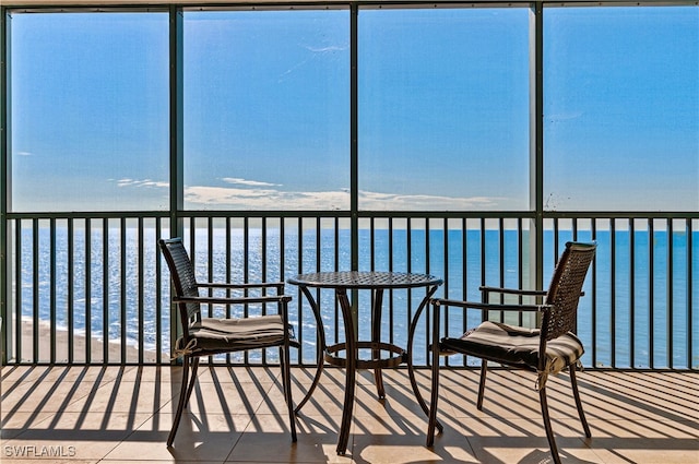 unfurnished sunroom with a water view and a view of the beach