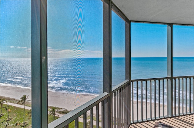 unfurnished sunroom with a water view and a view of the beach