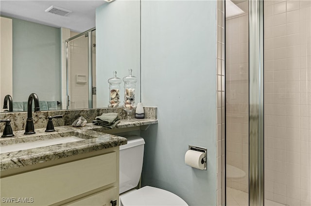 bathroom with a shower with door, vanity, and toilet