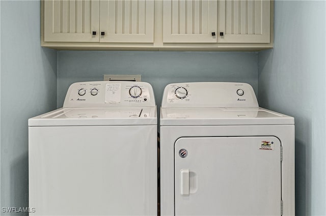 clothes washing area with cabinets and washer and dryer