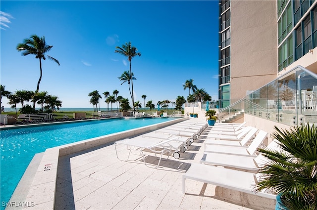 view of pool featuring a water view and a patio area