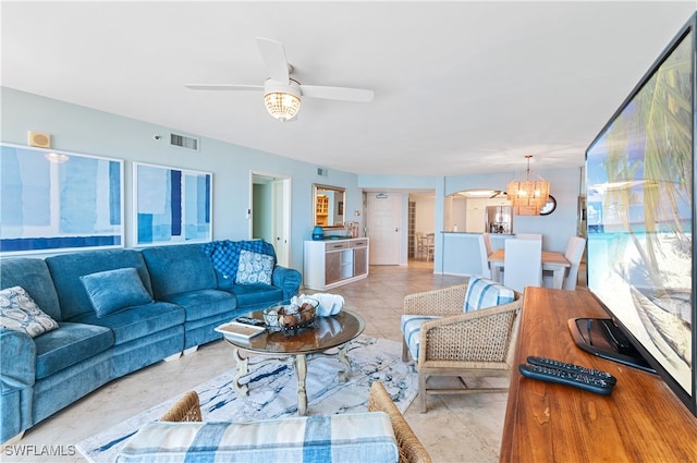 tiled living room with ceiling fan with notable chandelier