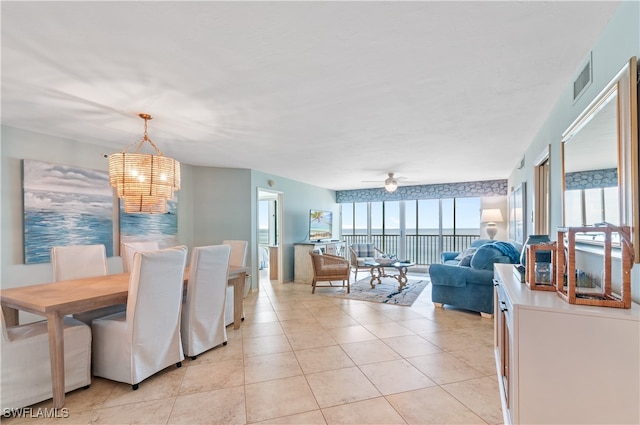 tiled dining area with a water view and ceiling fan with notable chandelier