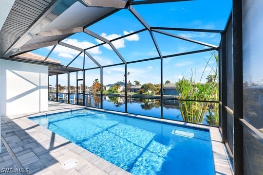 view of pool with a patio area, a water view, and a lanai