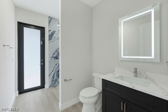 bathroom featuring toilet, hardwood / wood-style flooring, and vanity