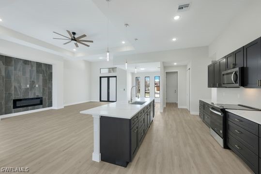 kitchen featuring a kitchen island with sink, stainless steel appliances, light hardwood / wood-style floors, and ceiling fan