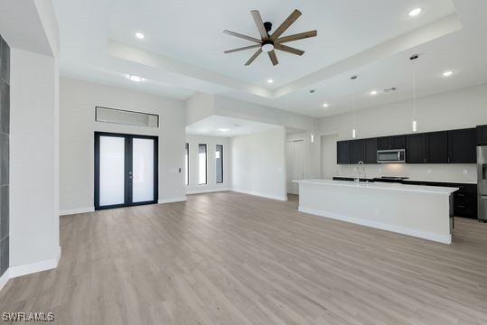 kitchen with appliances with stainless steel finishes, light wood-type flooring, and a kitchen island with sink