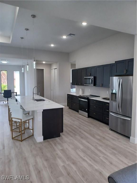 198 Gulfview Rd, Punta Gorda, FL 33950 - kitchen with stainless steel appliances, light wood-type flooring, decorative light fixtures, dark cabinets, and a breakfast bar area