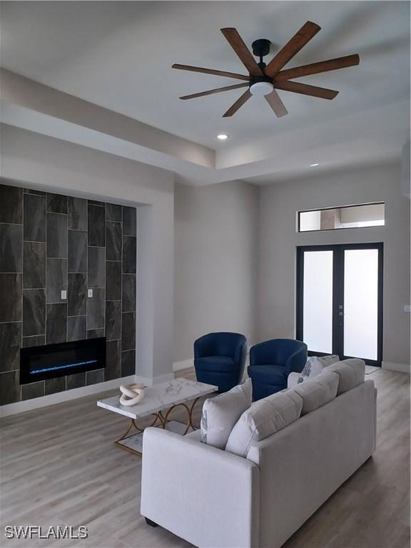 198 Gulfview Rd, Punta Gorda, FL 33950 - living room with wood finished floors, a ceiling fan, recessed lighting, a tiled fireplace, and a raised ceiling
