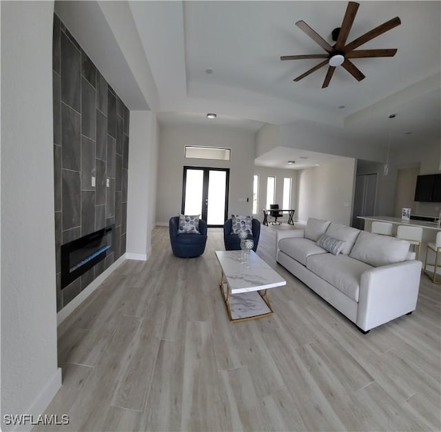 198 Gulfview Rd, Punta Gorda, FL 33950 - living area featuring ceiling fan, a raised ceiling, light wood-style floors, and a tiled fireplace