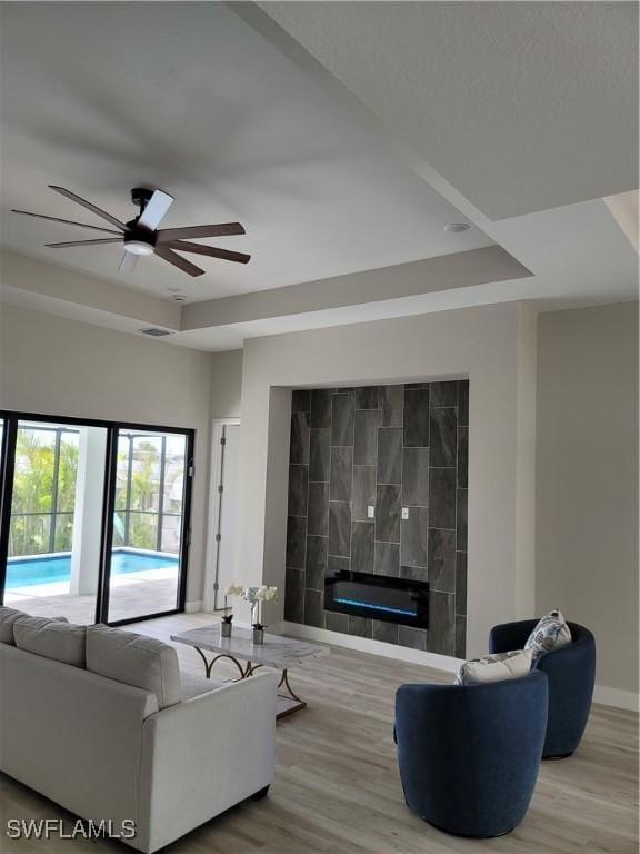 198 Gulfview Rd, Punta Gorda, FL 33950 - living area with wood finished floors, a ceiling fan, a tray ceiling, and a glass covered fireplace