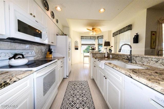 kitchen featuring sink, light wood-type flooring, white cabinets, light stone counters, and white appliances