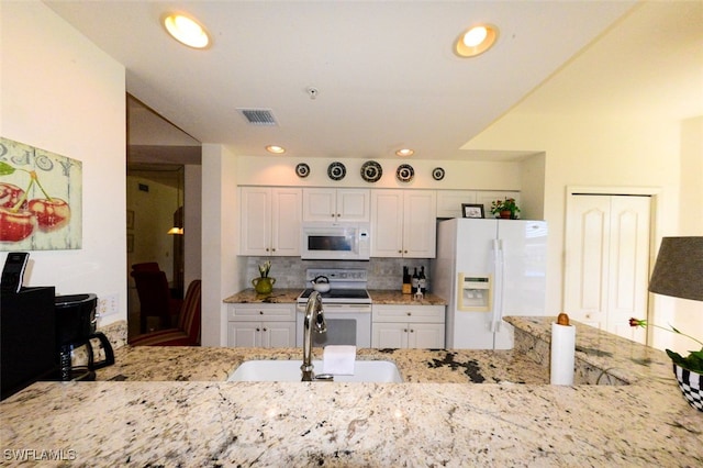 kitchen featuring backsplash, sink, white cabinetry, light stone counters, and white appliances