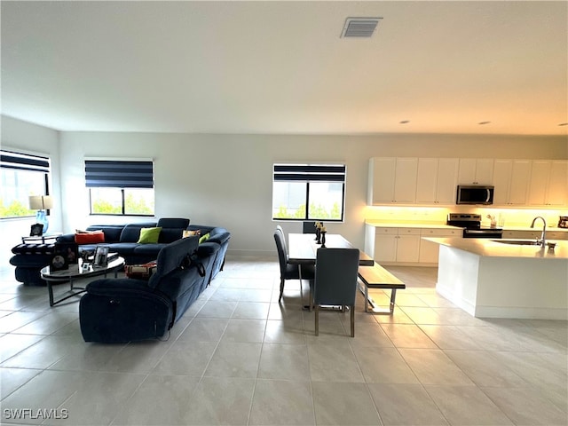 living room with light tile patterned floors, a wealth of natural light, and sink