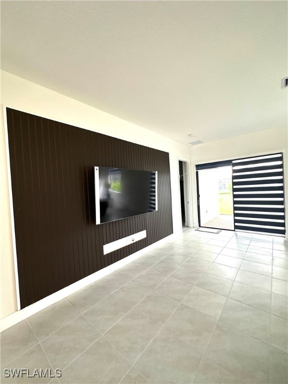 tiled empty room featuring wooden walls