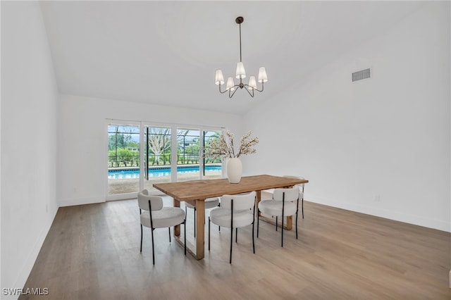 dining room with a chandelier, hardwood / wood-style flooring, and high vaulted ceiling