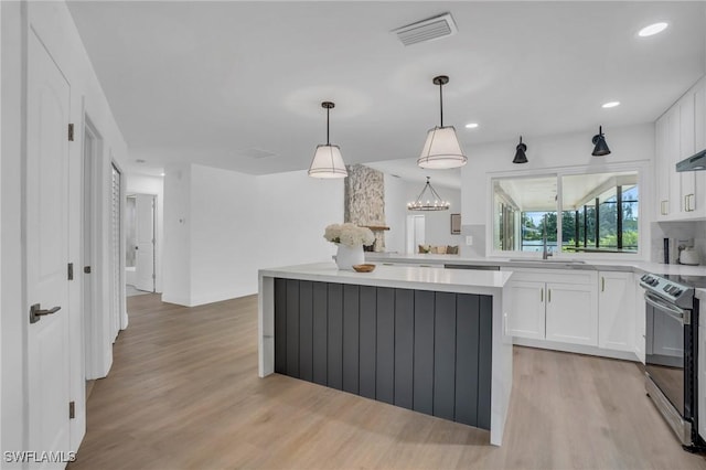 kitchen featuring electric range, visible vents, light countertops, white cabinetry, and a sink