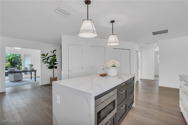 kitchen featuring pendant lighting, light hardwood / wood-style floors, stainless steel microwave, and a kitchen island