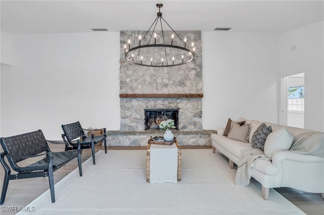 living room featuring a stone fireplace and an inviting chandelier