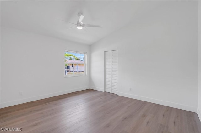 spare room featuring ceiling fan, vaulted ceiling, baseboards, and wood finished floors