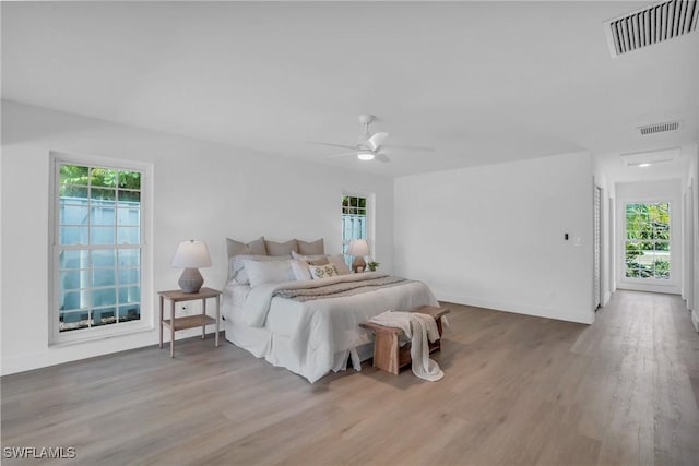 bedroom featuring ceiling fan, wood finished floors, visible vents, and baseboards