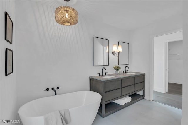 bathroom featuring double vanity, a soaking tub, a sink, and baseboards