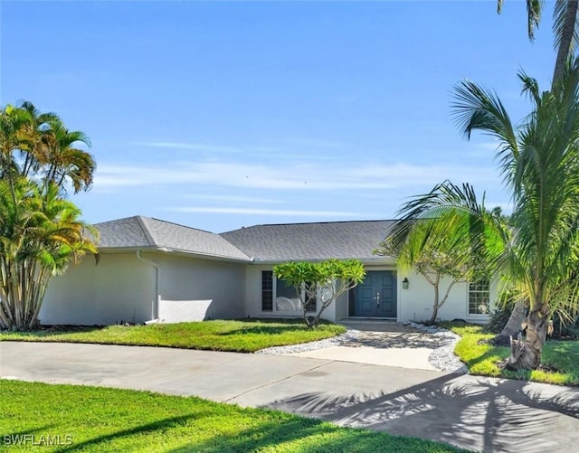 view of front of house with concrete driveway, a front lawn, french doors, and stucco siding