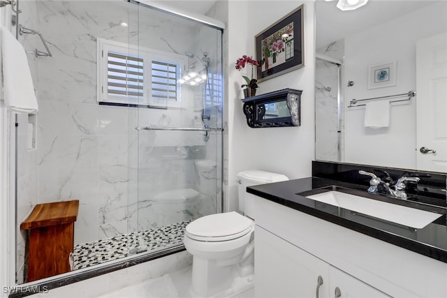 bathroom featuring a shower with door, vanity, and toilet