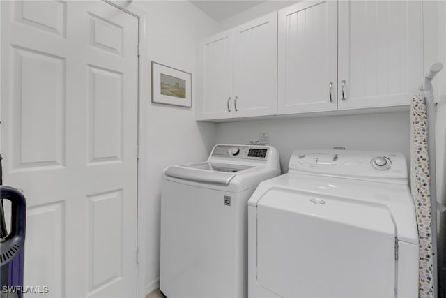 clothes washing area featuring washing machine and clothes dryer and cabinets