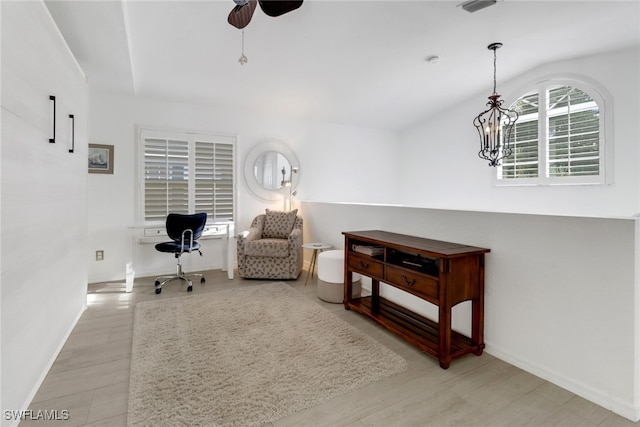 living area with light hardwood / wood-style floors and ceiling fan with notable chandelier