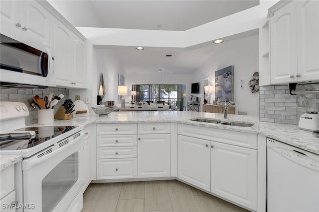 kitchen featuring white appliances, lofted ceiling, white cabinetry, and sink