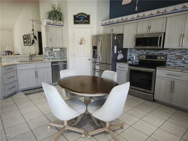 kitchen with light tile patterned floors, appliances with stainless steel finishes, a sink, and gray cabinetry