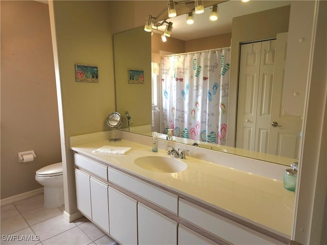 bathroom with tile patterned flooring, toilet, vanity, baseboards, and a closet