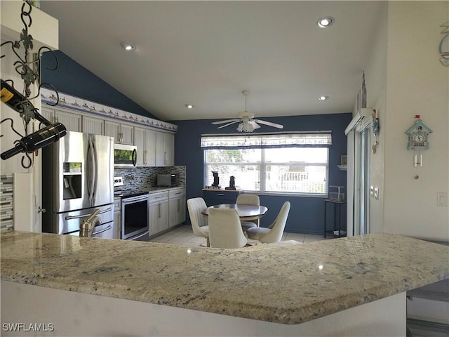 kitchen with stainless steel appliances, lofted ceiling, tasteful backsplash, light tile patterned flooring, and a peninsula