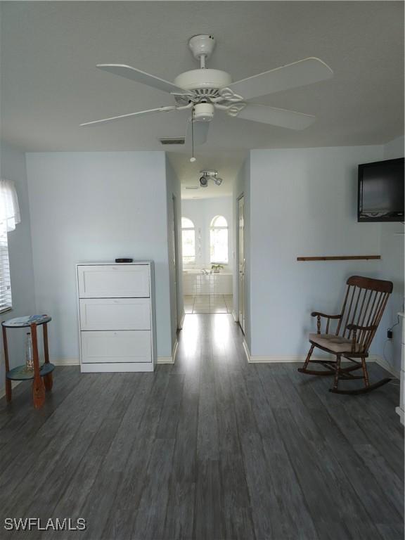 hall with dark wood-style flooring, visible vents, and baseboards