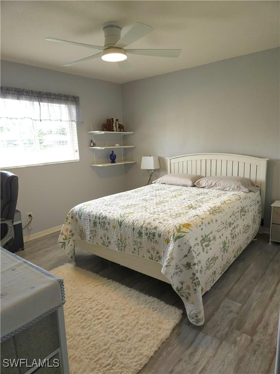 bedroom with dark wood-type flooring, a ceiling fan, and baseboards