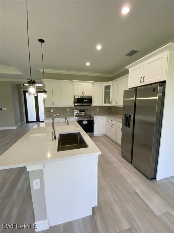 kitchen with white cabinets, stainless steel appliances, crown molding, decorative light fixtures, and sink