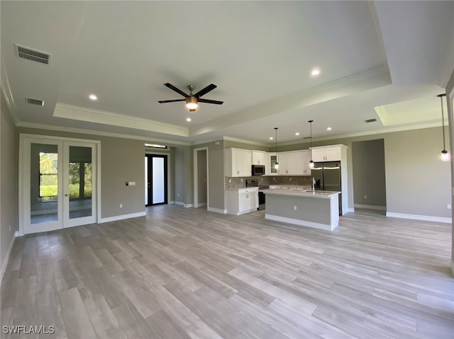 unfurnished living room with ceiling fan, a raised ceiling, and light hardwood / wood-style flooring